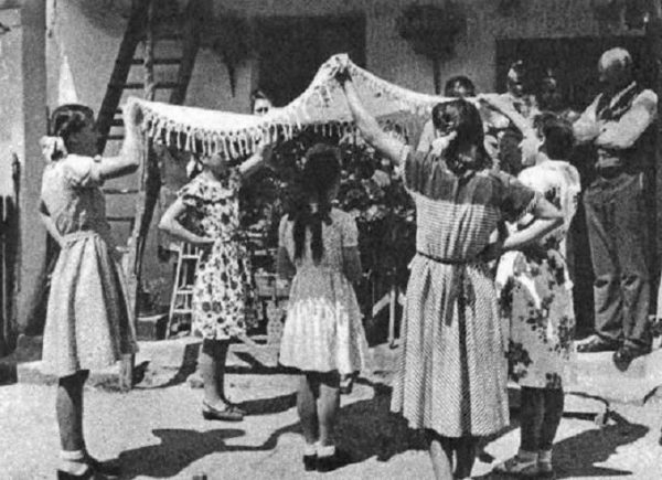 A felkeresett ház udvarán a pünkösdölők körülállják a királynét (Nemesládony, Vas m., 1952) (Forrás: Magyar Néprajzi Lexikon, mek.oszk.hu)